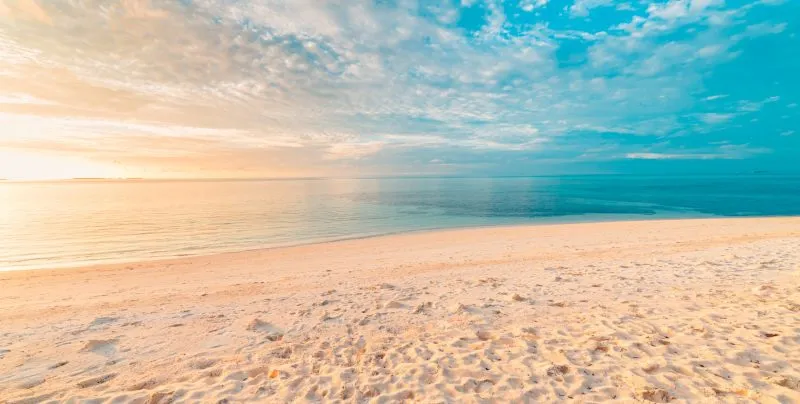 A serene white sand beach under a bright sky