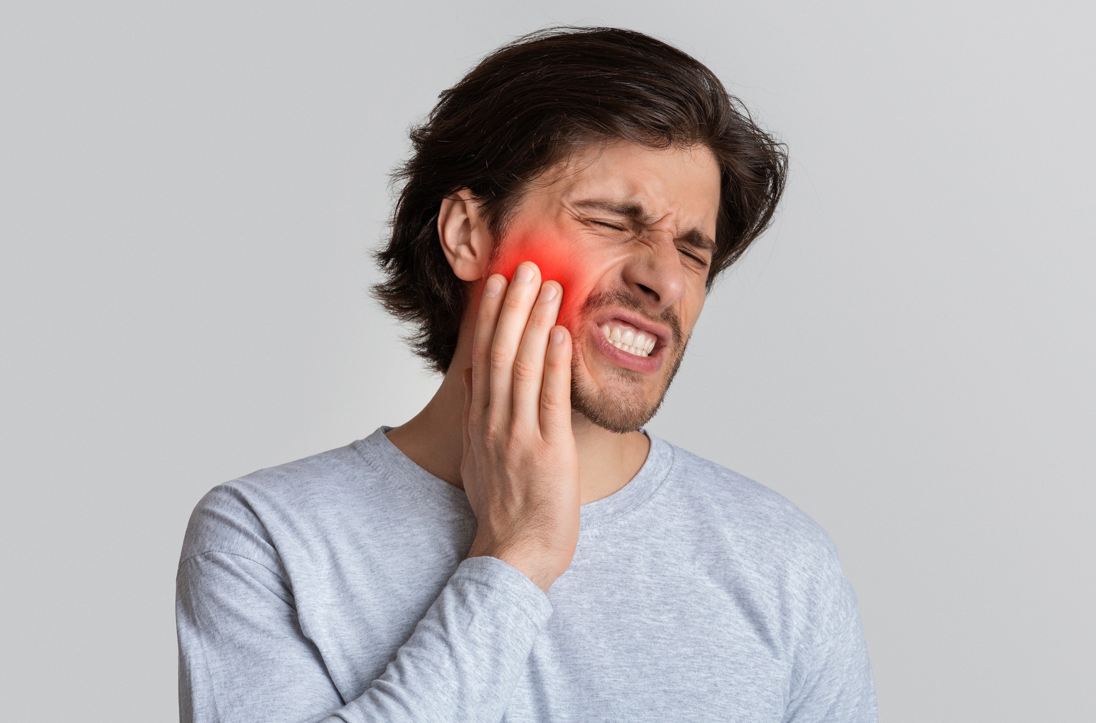 Man holding his face like he is having tooth or jaw pain